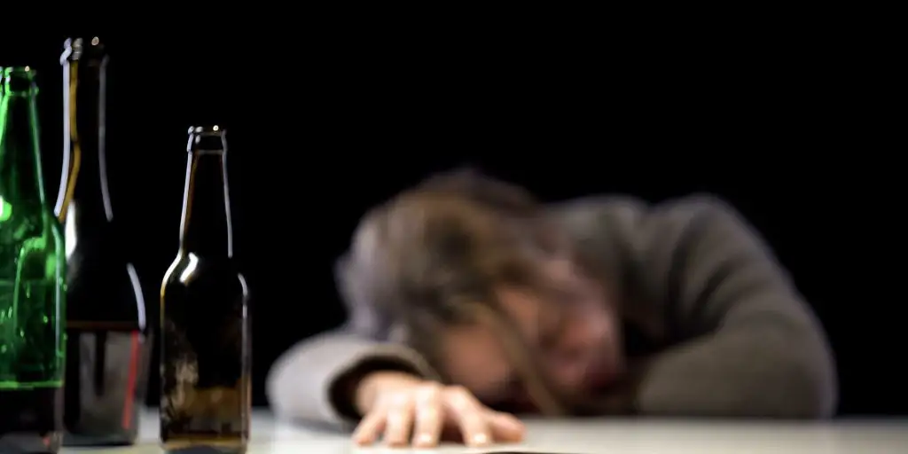 man sleeping near alcohol drinks