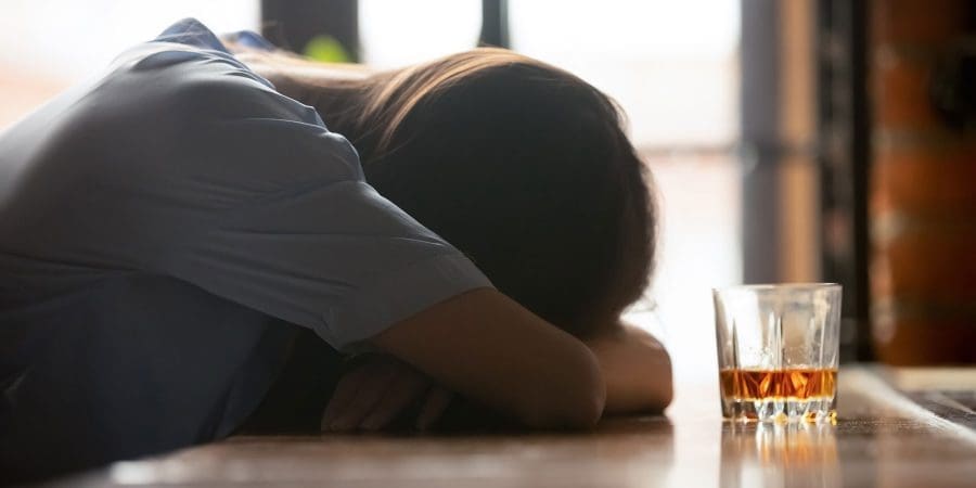 woman laying on the table near alcohol drink